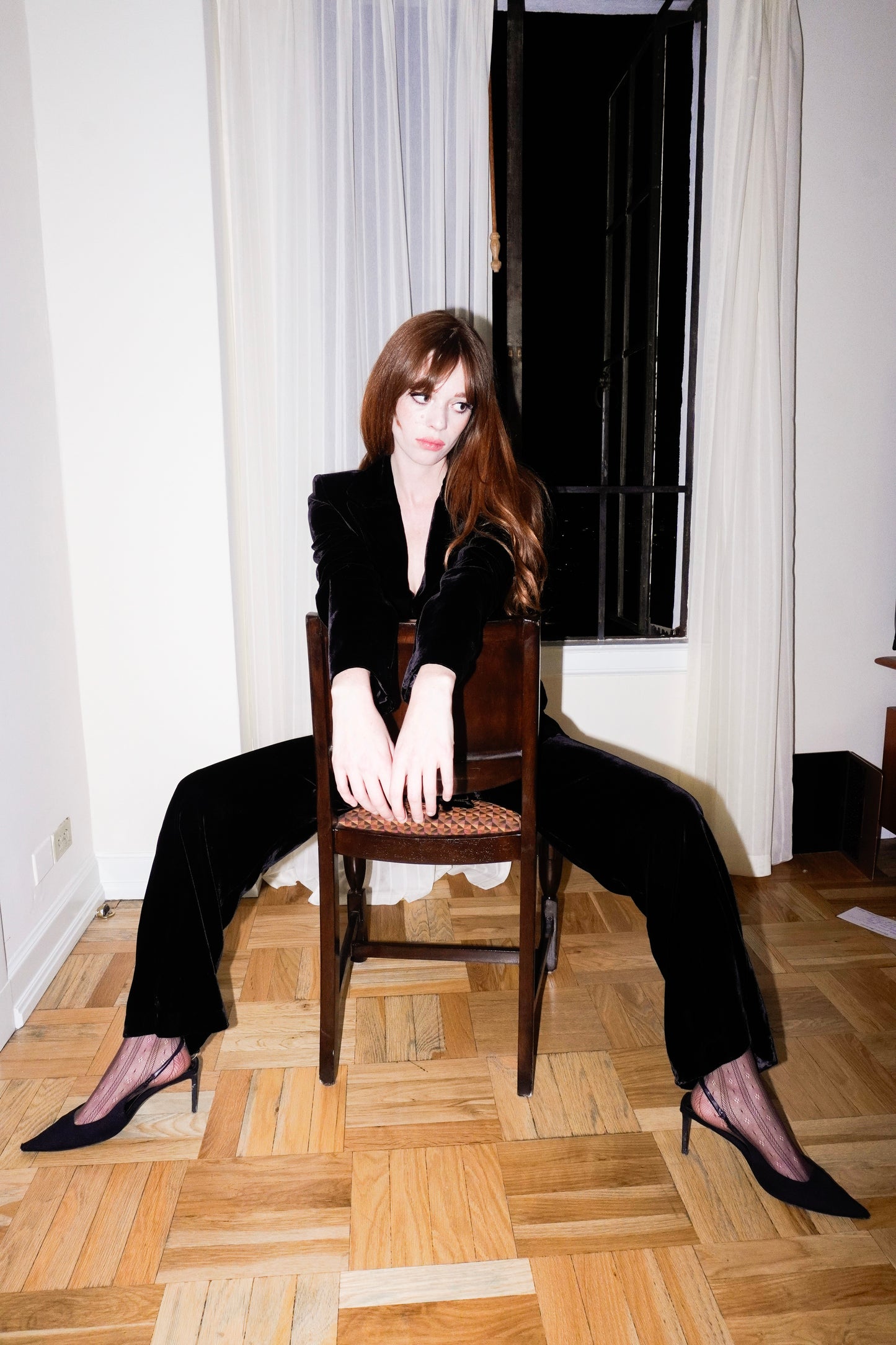 Woman sitting on a wooden chair in a room modelling all day velvet suit
