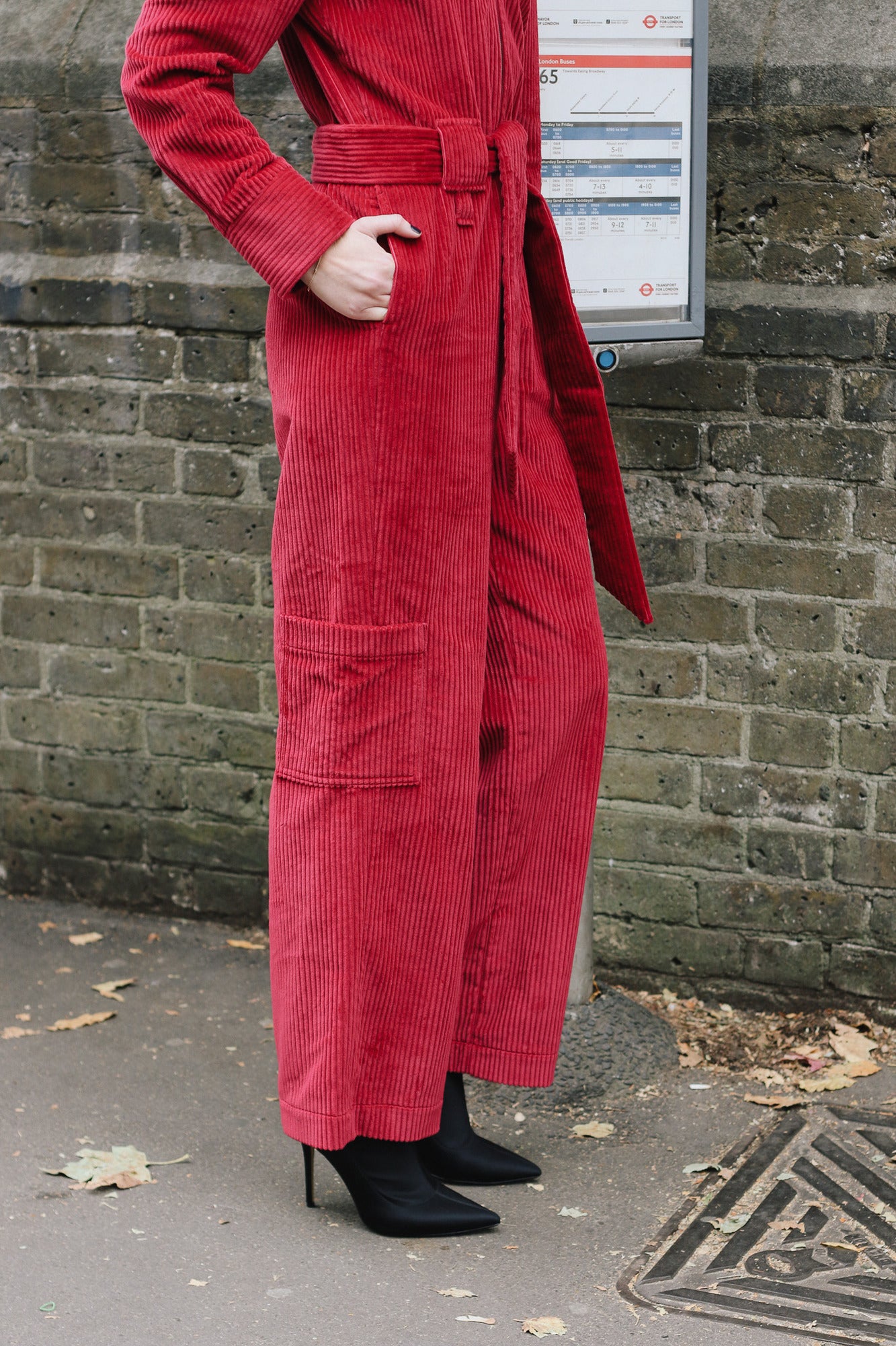Person wearing the red winston jumpsuit standing against a brick wall.