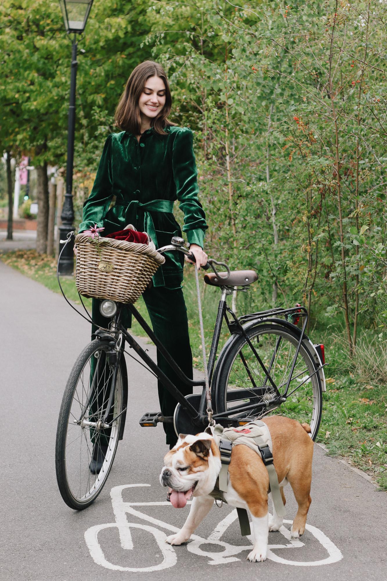 woman wearing the velvet Gentlewomen Trousers & Jacket in green with a bicycle and dog on a street.