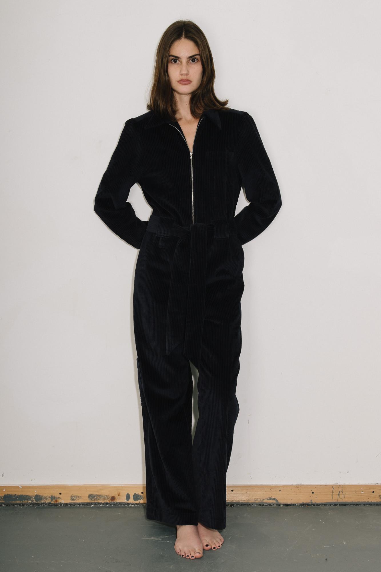 Woman wearing the black cord  Winston Jumpsuit against a plain white background