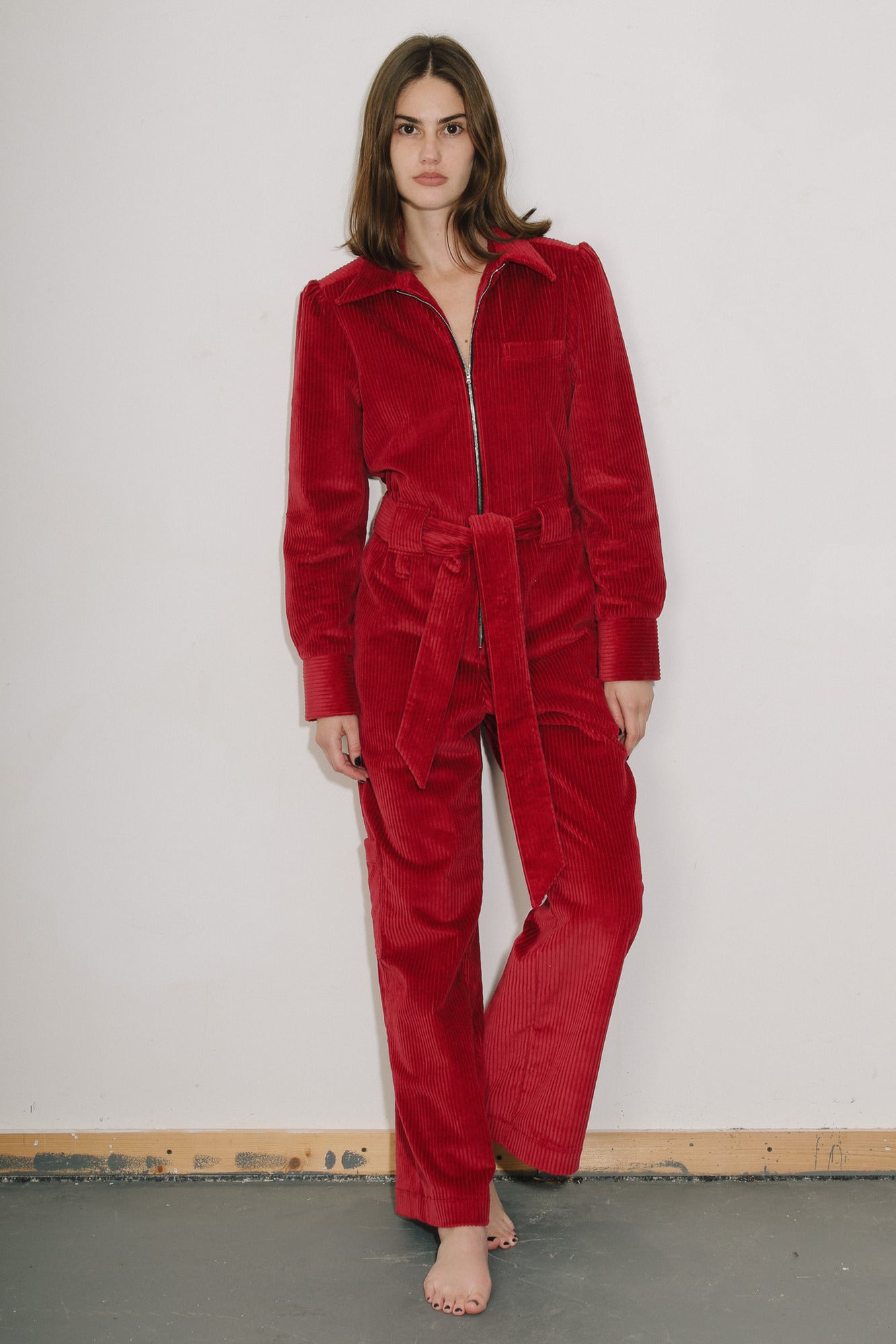 Woman wearing the red cord  Winston Jumpsuit against a plain white background