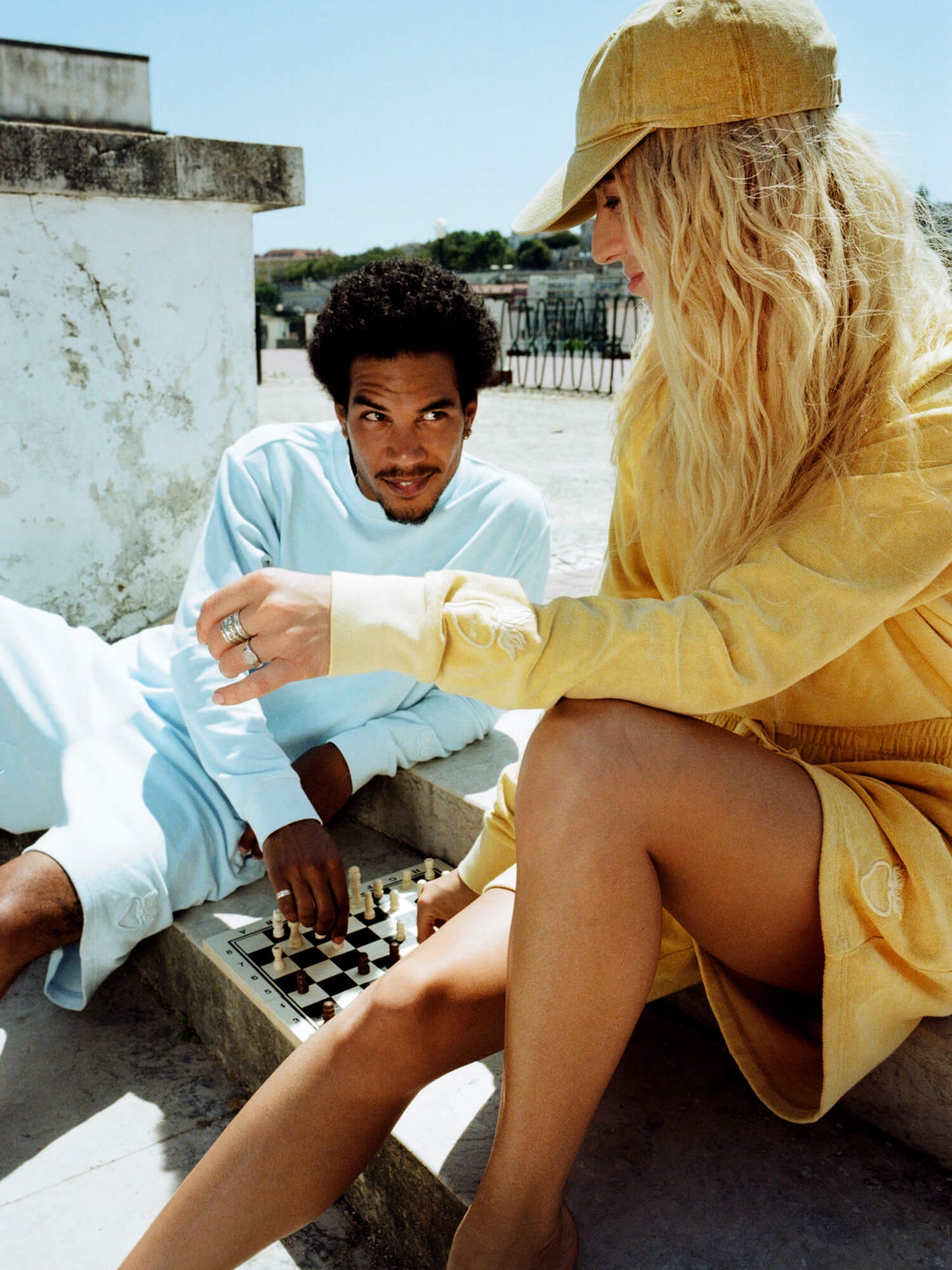 woman wearing Organic Terry Shorts in golden sand playing chess with man