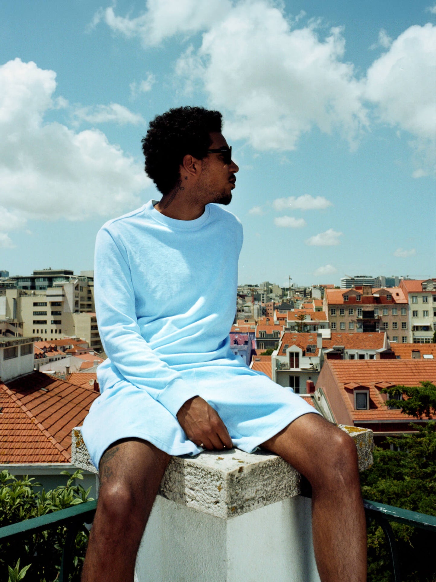 man sat on pillar wearing Organic Terry Shorts in sky blue