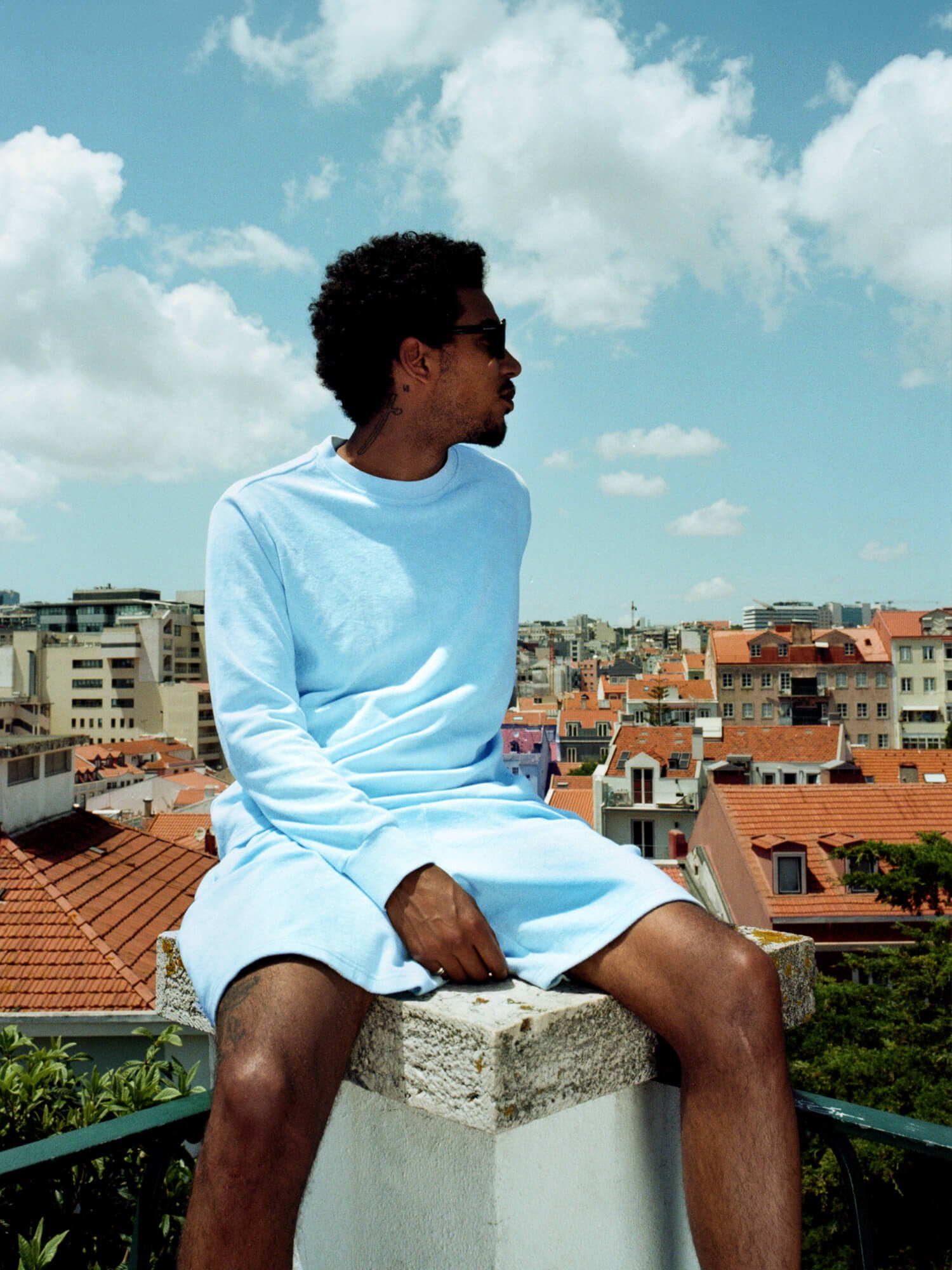 man sat on pillar wearing Organic Terry Shorts in sky blue
