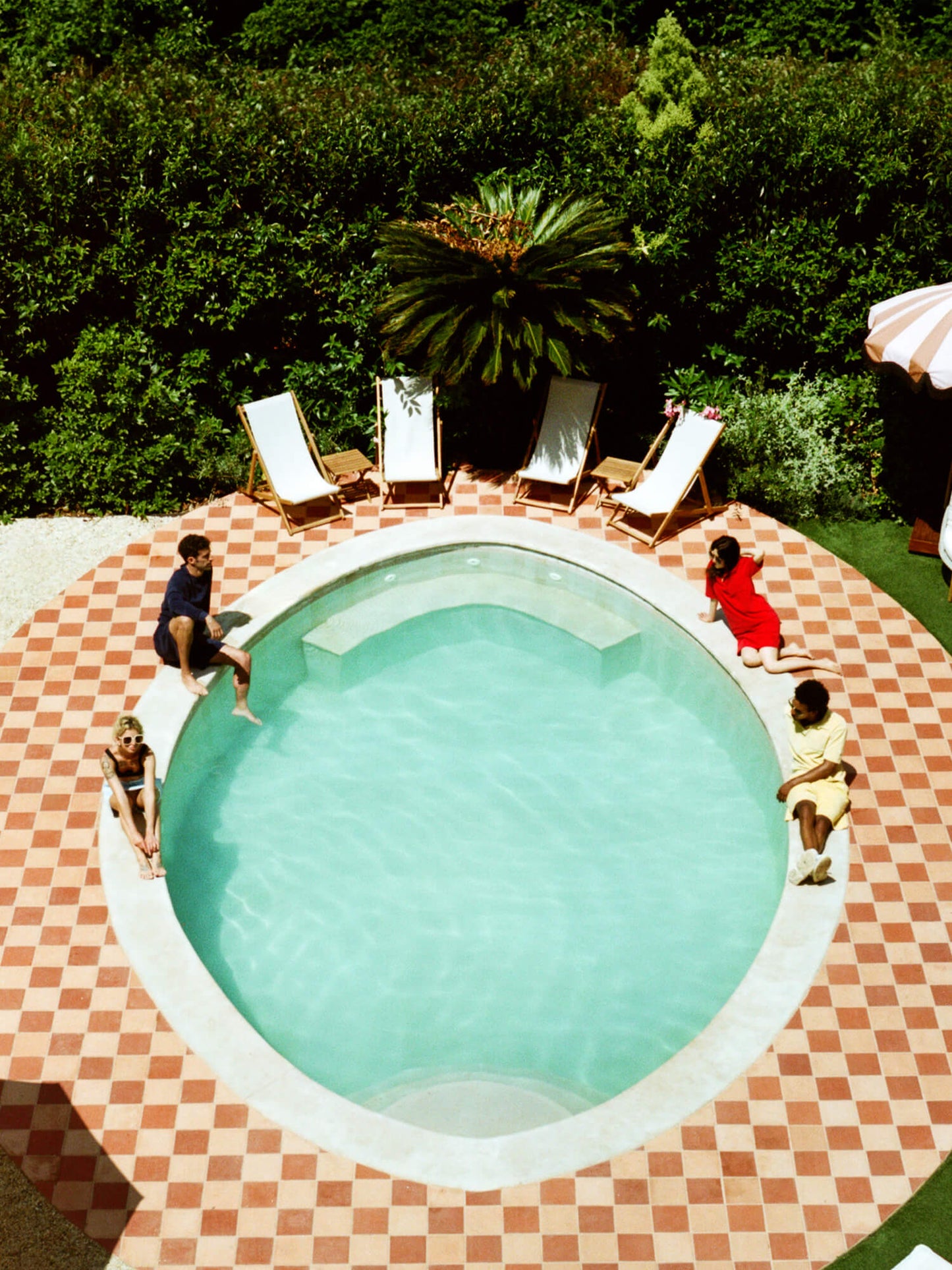man sat by circular pool with friends wearing Organic Terry Polo in Deep Ocean Blue
