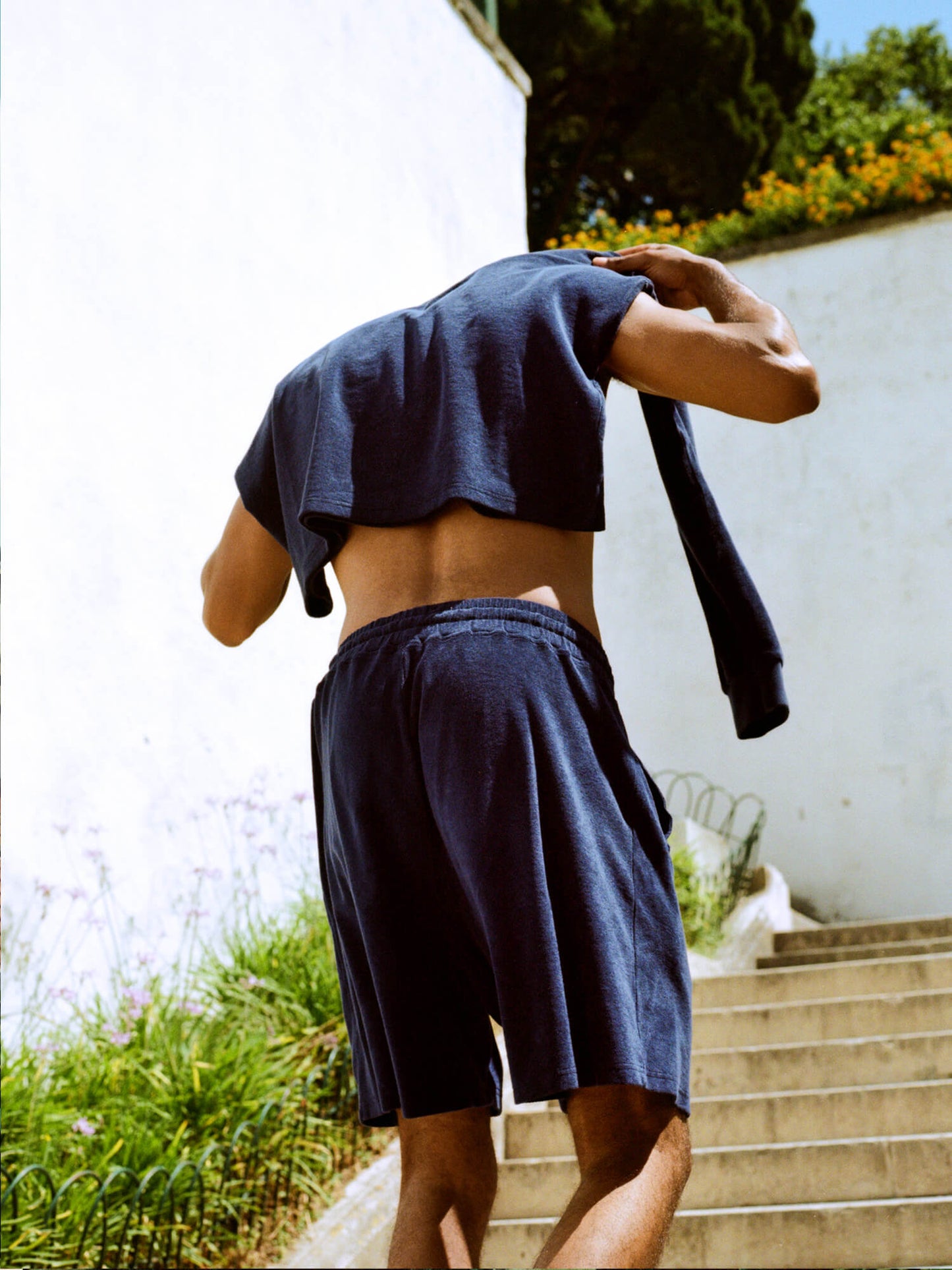 man with Organic Terry Long-sleeve in deep ocean blue draped over shoulders walking up stairs