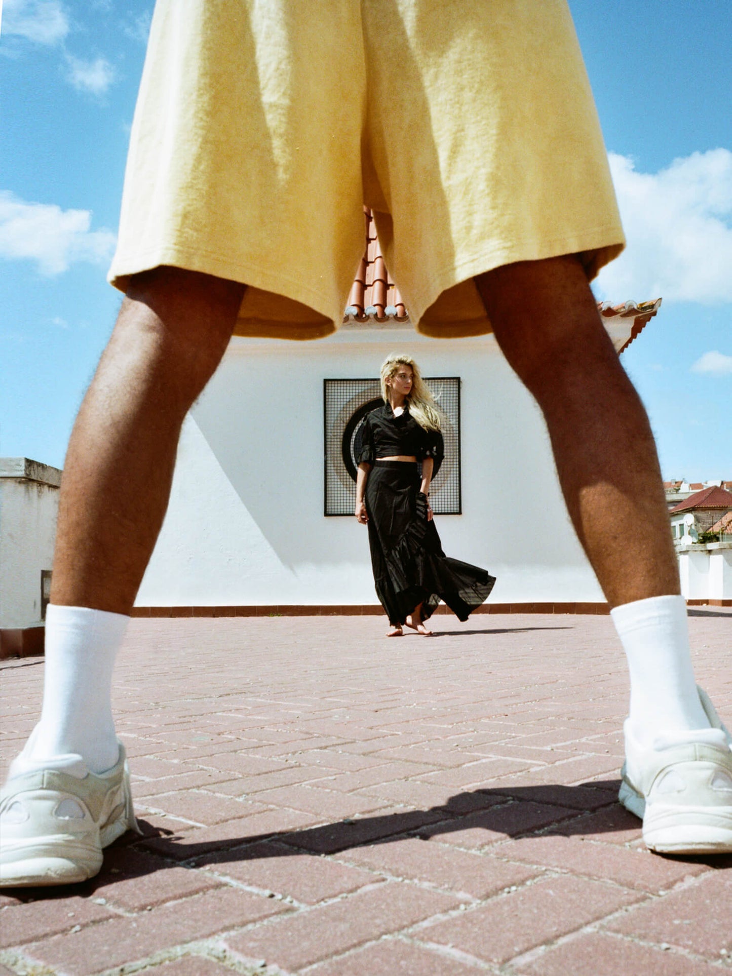 man wearing Organic Terry Shorts in golden sand wiht woman in background
